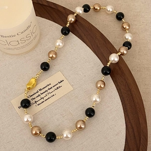 Close-up of vintage beaded necklace with black onyx and pearls on a wooden tray