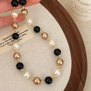 Close-up of vintage black onyx and pearl necklace with gold threaded spacers in hand