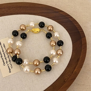 Retro multi-layer pearl necklace with black onyx beads and golden heart clasp on wood tray
