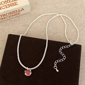 Detail of red zircon pendant on a silver adjustable link chain necklace with lobster clasp