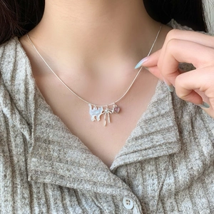 Collana d'argento con pendenti a gatto, fiocco e cuore rosa indossata al collo