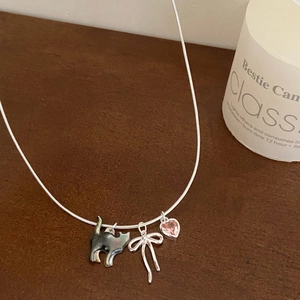 Detail of snake chain necklace with shell cat, silver bow, and pink heart charms
