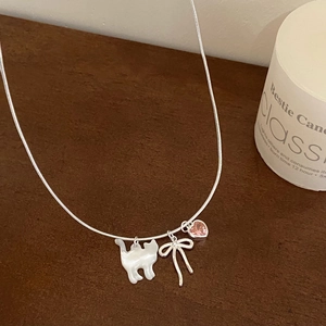 Close-up of shell cat and pink heart zircon pendant necklace with a silver bow detail