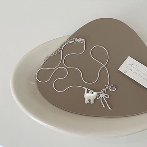 Dettaglio della collana con gatto in argento, fiocco e zircone viola su vassoio