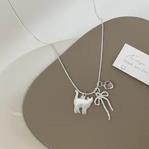 Dettaglio collana in argento con gatto di conchiglia, cuore rosa e ciondolo a fiocco