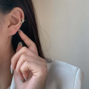 Manchette d'oreille dorée avec trois zircons dégradés, portée avec un blazer blanc
