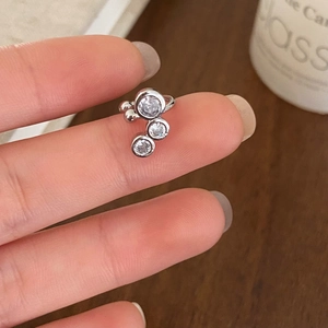 Gros plan d'une bague d'oreille en argent avec trois zircons ronds et brillants