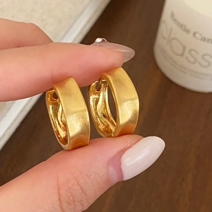 Detailed close-up of matte brushed gold hoop earrings with secure pin closure design