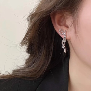 Orecchini a fiocco d'argento con lunghe nappe indossati da una modella per un look raffinato