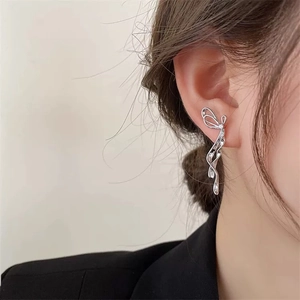 Dettaglio di orecchini a fiocco d'argento con nappe eleganti sull'orecchio della modella