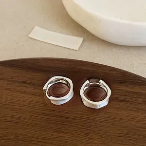 Macro shot of minimalist silver twisted hoop earrings with a matte brushed finish texture