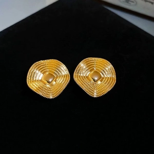 Macro detail of gold-plated square earrings with retro concentric embossed texture