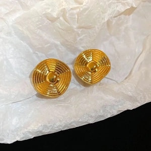 Detail of vintage gold-plated earrings showing textured circular ripple patterns