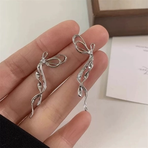 Dettaglio di orecchini a fiocco con nappe in argento, zircone e linee ondulate eleganti