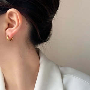 Elegant gold geometric earrings with textured wave design shown on a model