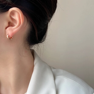 Minimalist gold hoop earrings with hammered texture shown on model in white blazer