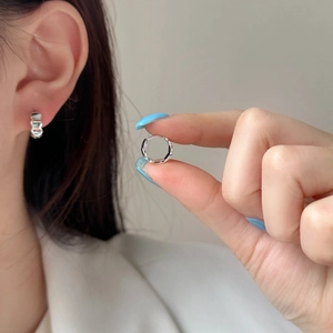 Minimalist silver wavy textured hoop earrings shown on ear for size and detail