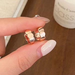 Detailed view of rose gold huggie hoop earrings with unique tiered textured design