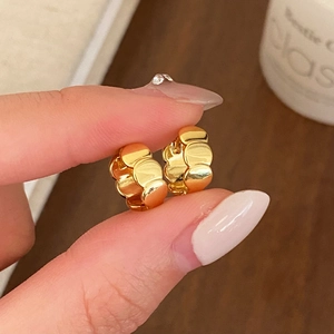 Detailed close-up of chunky gold hoop earrings with wave textured metal finish