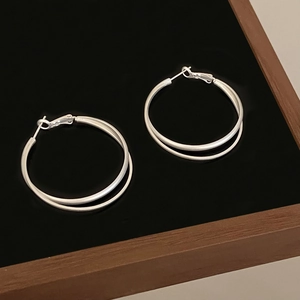 Silver double hoop earrings with a layered twist design on a black velvet display