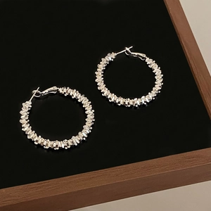 Close-up of silver double spiral hoop earrings with textured finish on black surface