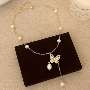 Detailed view of a gold butterfly necklace with freshwater pearls on a jewelry box