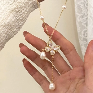 Close-up of golden butterfly necklace with cubic zirconia, tassels and freshwater pearls