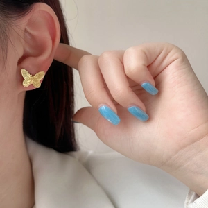 Elegant gold butterfly stud earrings with matte brushed finish shown on ear