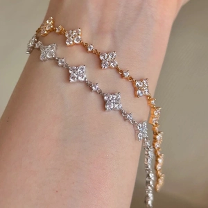 Detailansicht eleganter Kleeblatt-Armbänder mit Zirkon-Inlays in Gold und Silber
