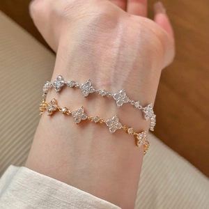 Makro-Detail von Kleeblatt-Armbändern in Gold und Silber mit funkelndem Zirkonia-Besatz
