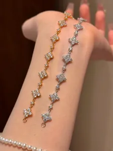 Nahaufnahme von Gold- und Silber-Glücksklee-Armbändern mit funkelndem Zirkonia am Handgelenk
