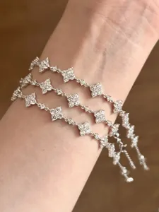 Detail von verstellbaren Silber-Kleeblattarmbändern mit Zirkonia-Mikropavé am Handgelenk