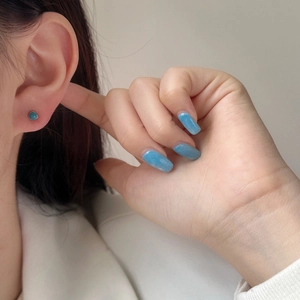 Close-up of minimalist teardrop stud earrings with turquoise enamel on silver base