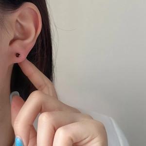 Elegant red gemstone stud earrings in gold plating shown on a model with a clean profile