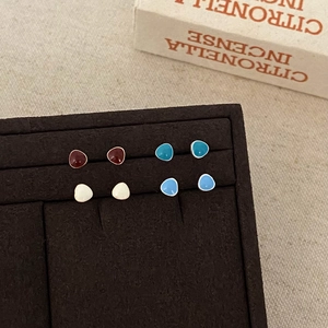 Detail of four pairs of small triangle enamel stud earrings in assorted retro colors