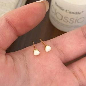 Close-up of small heart enamel stud earrings held in hand for scale and detail