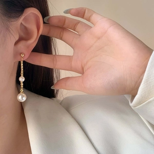 Elegant gold double pearl drop earrings featuring long chains for a minimalist look