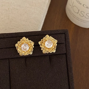 Close-up of vintage gold flower earrings with zircon center on brown velvet box