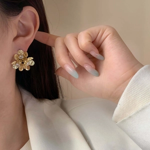 Elegante Blumen-Ohrstecker mit gehämmerter Metallstruktur und Zirkonia am Ohr getragen