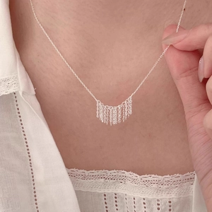 Elegant silver tassel pendant necklace with multiple fine chains shown on a model
