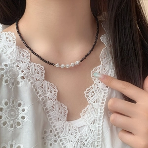 Elegant black beaded necklace with silver hollow sphere pendants on a model's neck