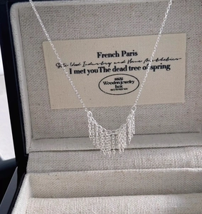 Detailed view of elegant silver tassel pendant with fine metal chains on jewelry box