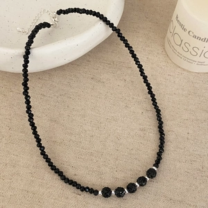 Detail of black faceted bead necklace featuring textured spheres and silver lobster clasp
