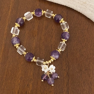 Detailed shot of amethyst beaded bracelet with shell flowers on rustic wood background