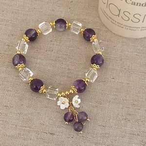 Detailed shot of beaded crystal bracelet with purple stones and shell flower pendants