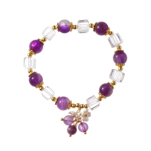 Minimalist beaded crystal bracelet with purple stones and gold floral accents on white