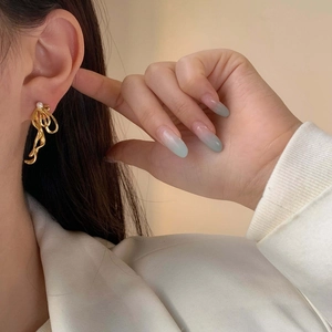 Elegant gold bow-shaped ribbon earrings with pearl accent worn with business attire