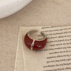Détail d'une bague ajustable en émail rouge foncé sur un fond esthétique vintage