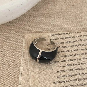 Détail d'une bague ajustable en émail noir au design vintage français sur tissu lin