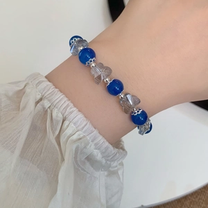 Bracelet en perles de verre bleues avec pendentif ours sur le poignet d'une femme